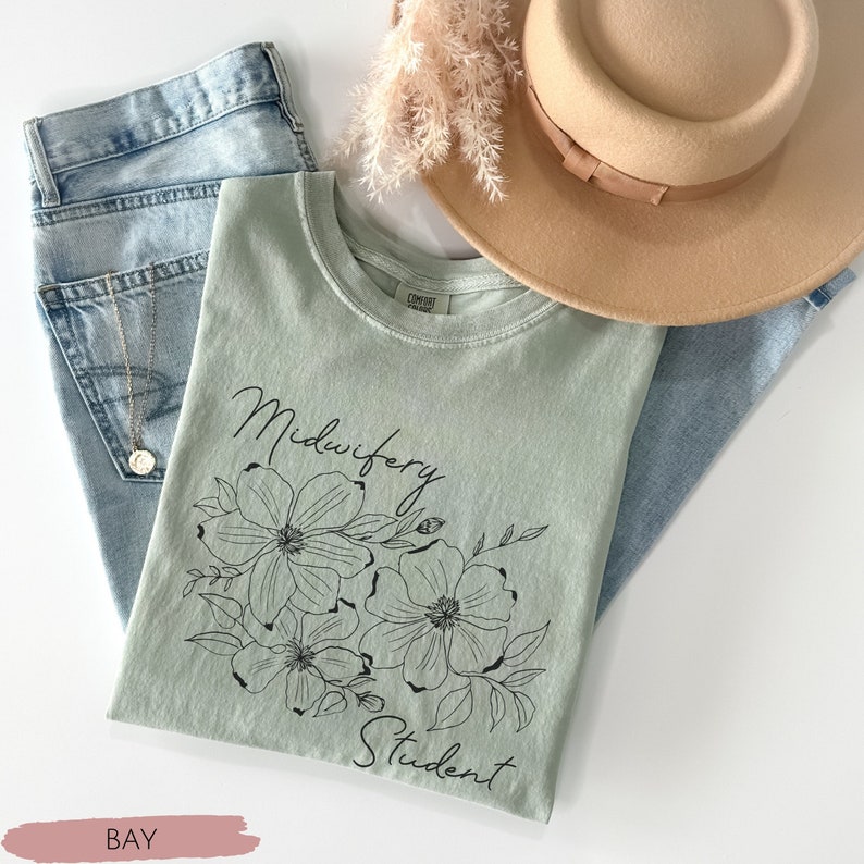 Może przedstawiać: Jasnozielony t-shirt z czarnym wzorem kwiatowym i tekstem "Midwifery Student".