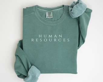 May include: A light green sweatshirt with the text "HUMAN RESOURCES" printed in white on the front.