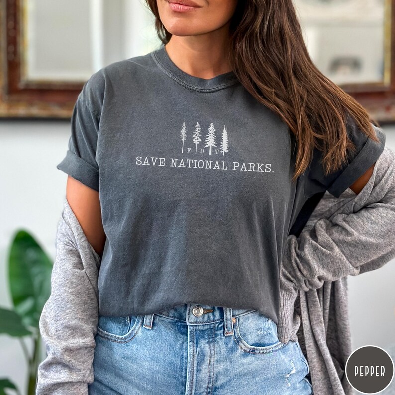 May include: A dark gray t-shirt with a white graphic of five trees and the text "SAVE NATIONAL PARKS."