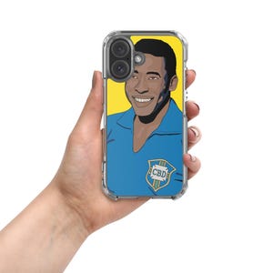May include: Clear phone case featuring a vibrant illustration of a smiling man in a blue shirt against a yellow backdrop. The design includes a shield with the letters "CBD". The case is held in a hand.
