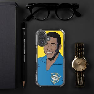 May include: Clear phone case featuring a smiling portrait of a man in a blue shirt against a yellow background. The case has a CBD logo. A gold watch and black glasses are also visible.