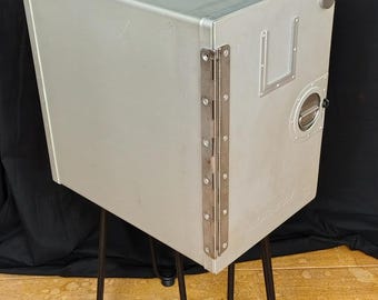 Contenedor de cocina de Cubana de Aviación convertido en mesa auxiliar con patas de metal.