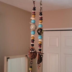 May include: Two beaded ceiling fan pull chains. Each chain features a mix of wooden, turquoise, and glass beads. The chains end with copper-colored cones and leather tassels in shades of yellow and green.