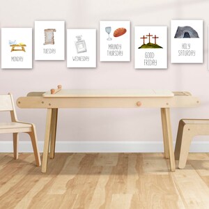 May include: A set of eight printable wall art prints featuring illustrations and text related to the Christian holiday of Easter. The prints are displayed on a wall above a wooden table and chairs.