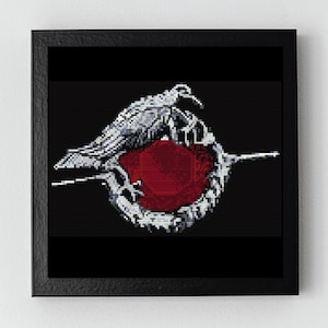 May include: A black and white cross-stitch design of a bird with a red circle in the center. The bird is stylized and appears to be holding the circle in its beak.