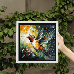 May include: A framed painting of a hummingbird in flight with a colorful abstract background. The hummingbird is painted in shades of orange, white, and red, with its wings spread wide. The background is a mix of green, blue, and yellow.