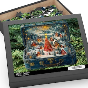 May include: A 16x20 inch puzzle in a black box, featuring a winter village scene inside a vintage blue suitcase. The puzzle shows a Christmas tree, snow-covered houses, and mountains. The box also contains puzzle pieces.