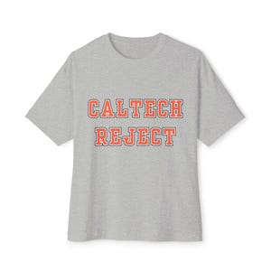 May include: A heather gray t-shirt with the words "CALTECH REJECT" printed in orange block letters. The text is outlined in a darker orange. The shirt has short sleeves and a crew neck.