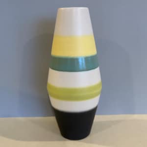Peut inclure: Un vase décoratif de forme conique, orné de bandes horizontales de couleurs. Le haut est blanc, suivi de jaune, vert d'eau, blanc, vert clair et une base noire. Ce vase en céramique est un élément de décoration élégant.