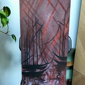 May include: Abstract painting of ships in a harbor with a red and brown background. The ships are black and the water is a light blue.