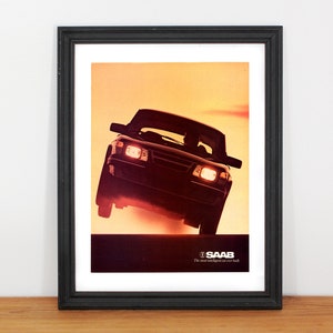 May include: A black Saab car driving on a road with a sunset in the background. The car's headlights are on and the text "SAAB The most intelligent car on the road" is visible at the bottom of the image.