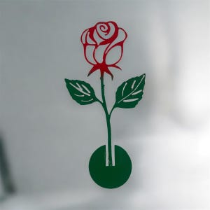 May include: A stylized illustration of a red rose with green leaves and stem. The rose is in full bloom, with detailed petals. The stem extends into a green circular base, creating a simple, elegant design.