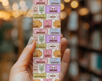 May include: A colorful bookmark with a repeating pattern of ticket stubs. Each ticket stub has a different genre of literature written on it, including thriller, romance, sci-fi, fantasy, horror, poetry, and contemporary.