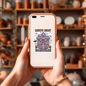 May include: A white phone case featuring a purple haunted house illustration with the text "Haunted Library". The house is surrounded by ghosts and bats.