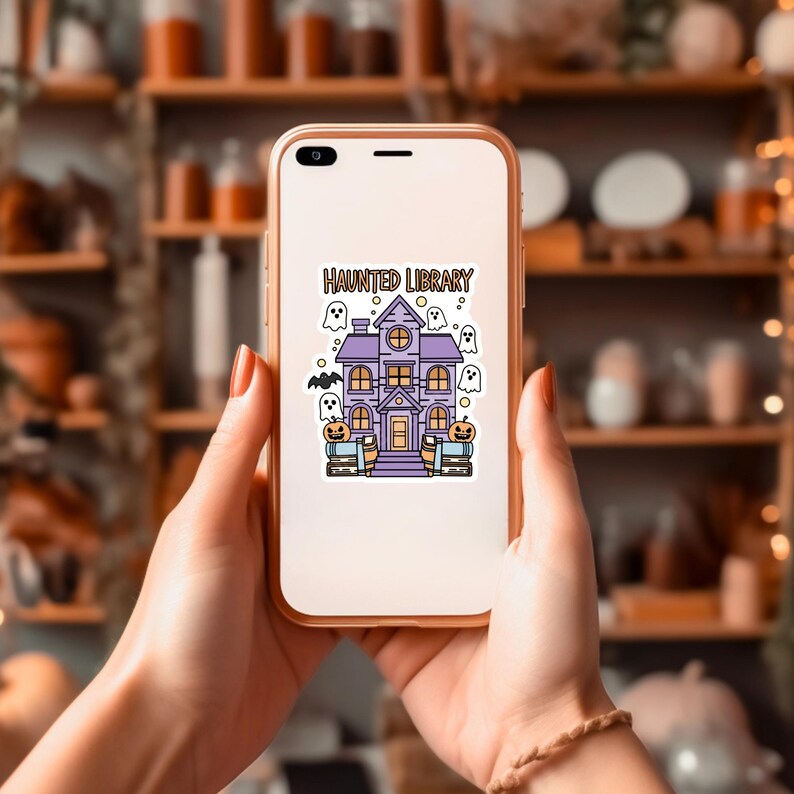 May include: A white phone case featuring a purple haunted house illustration with the text "Haunted Library". The house is surrounded by ghosts and bats.