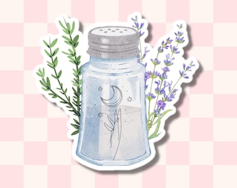 May include: A glass salt shaker with a silver lid and a hand reaching up towards a crescent moon and stars. The shaker is surrounded by sprigs of lavender and rosemary.