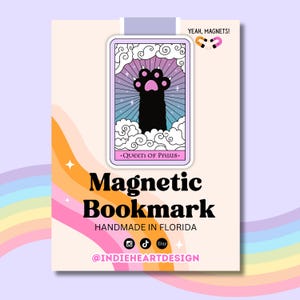 May include: A pink and blue illustrated card with a black paw print reaching up to the clouds. The card says "Queen of Paws" and "Magnetic Bookmark Handmade in Florida" with social media icons and the text "@indieheartdesign".