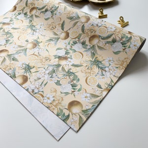 May include: A sheet of yellow wrapping paper with a floral pattern featuring white flowers and yellow lemons. The paper has a subtle texture and is perfect for wrapping gifts.