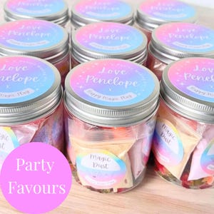 May include: A collection of clear plastic jars with silver screw-top lids, each featuring a circular label with a gradient background in pink, purple, and blue. The labels display the text Love Penelope, Potion Making Kit, and Happy Magic Play.