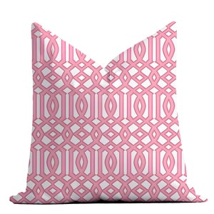 May include: A square decorative pillow with a repeating pink and white geometric trellis pattern. The pillow has a soft, inviting appearance, perfect for adding a touch of color and design to any living space.
