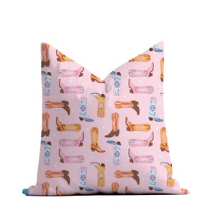May include: Pink pillow with a pattern of colorful cowboy boots. The boots are in various shades of pink, orange, and blue.