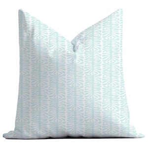 Puede incluir: Una almohada de tiro azul claro con un patrón blanco repetitivo de hojas estilizadas.
