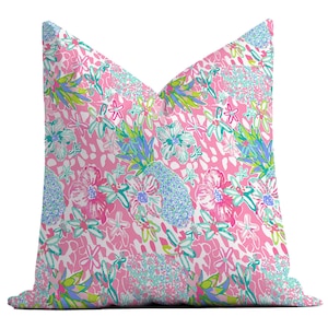 May include: Pink pillow with a floral print featuring pink, blue, and green flowers on a white background with pink and white animal print accents.