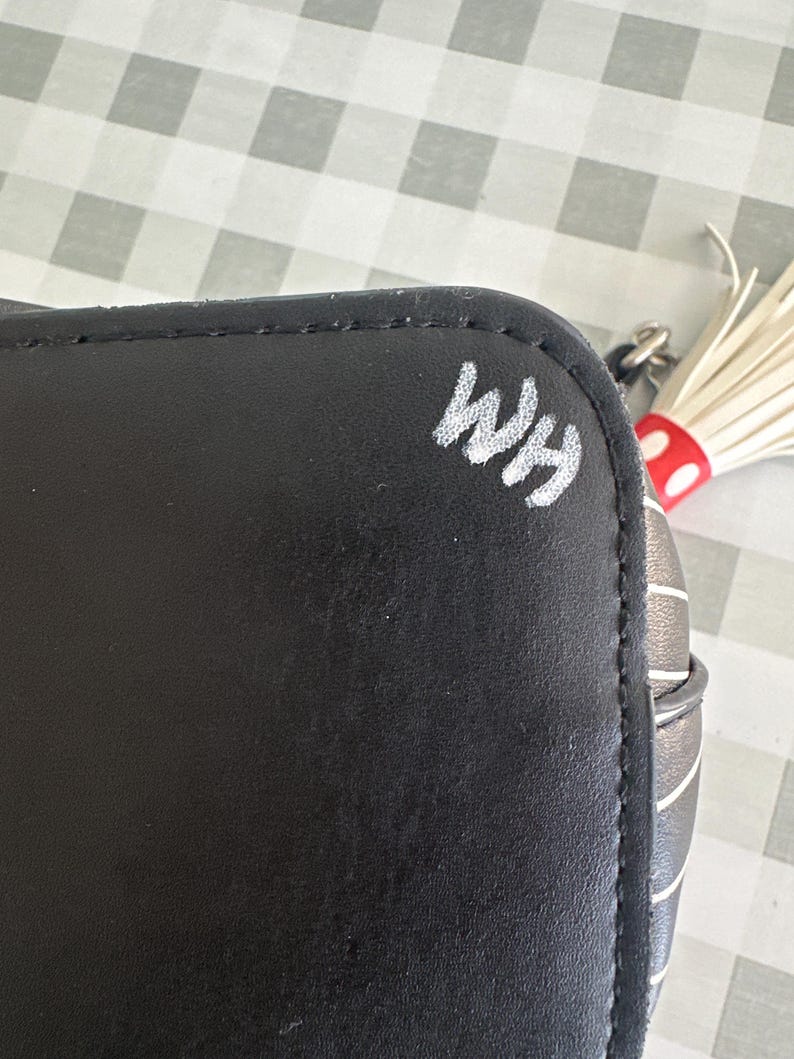May include: Black and white striped handbag with a white tassel and the initials "WHM" written in white on the side.