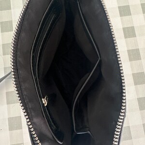 May include: Black leather crossbody bag with a zipper closure and two interior pockets.