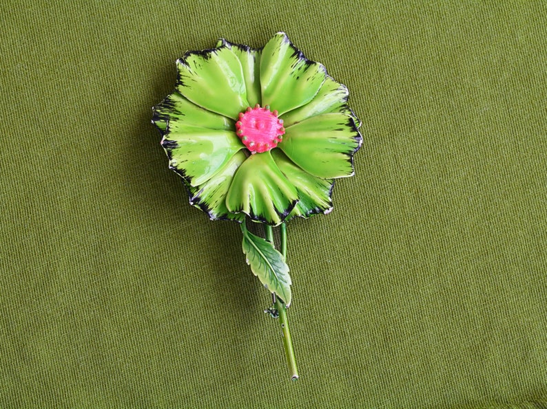 Retro 60s colorful metal flower brooch is large bright green with black edges, pink center, long green stem and one green leaf.