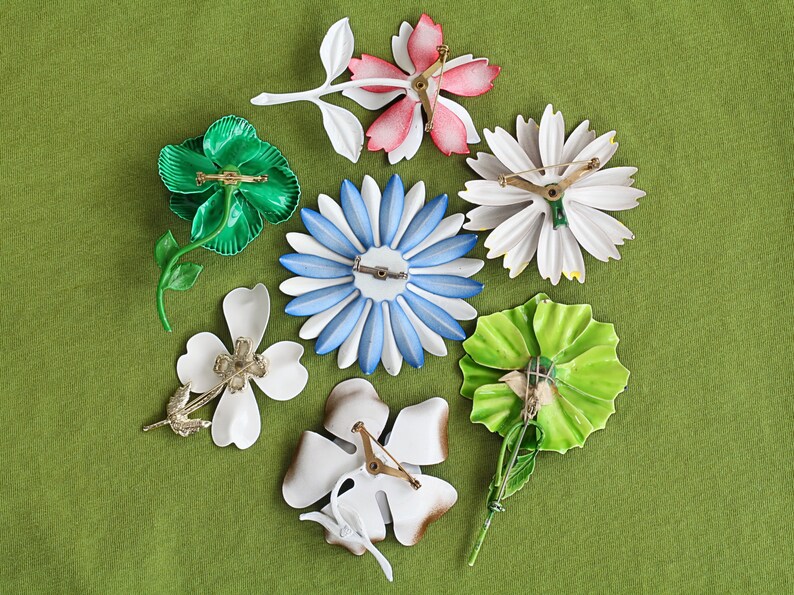 Retro colorful metal flower brooches in seven varieties with backs showing.