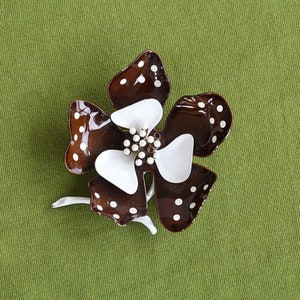 Retro 60s colorful metal flower brooch has five brown curled in petals with white polka dots. Inside are white curled in smaller petals. Center pistils in white and short white stem.