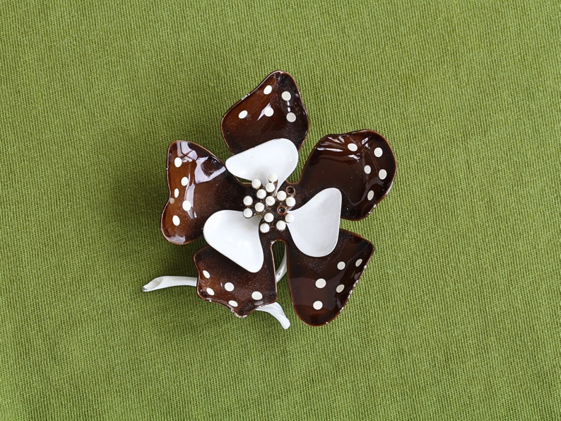 Retro 60s colorful metal flower brooch has five brown curled in petals with white polka dots. Inside are white curled in smaller petals. Center pistils in white and short white stem.