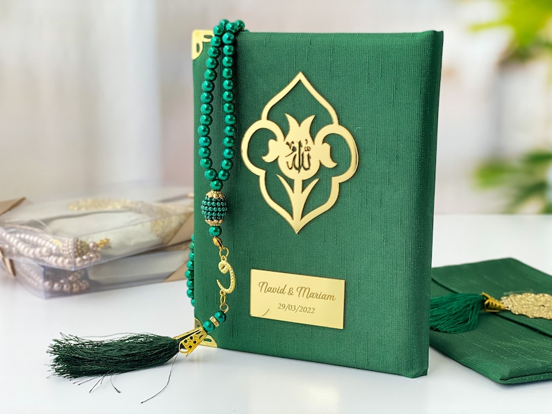 Pu&ograve; includere: Un libro di preghiere verde con un'iscrizione dorata e un fiocco verde. Il libro presenta un design dorato sulla copertina e un'iscrizione dorata che recita "Navid & Mariam 29/03/2022". Il libro &egrave; accompagnato da una collana di preghiera con perline verdi e un ciondolo dorato.