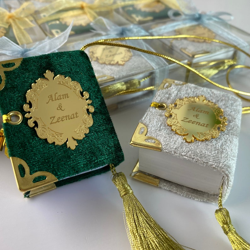 May include: Two small velvet-covered books with gold trim and a gold plaque with the names "Alam & Zeenat" on each. The books are attached to gold cords with gold tassels.