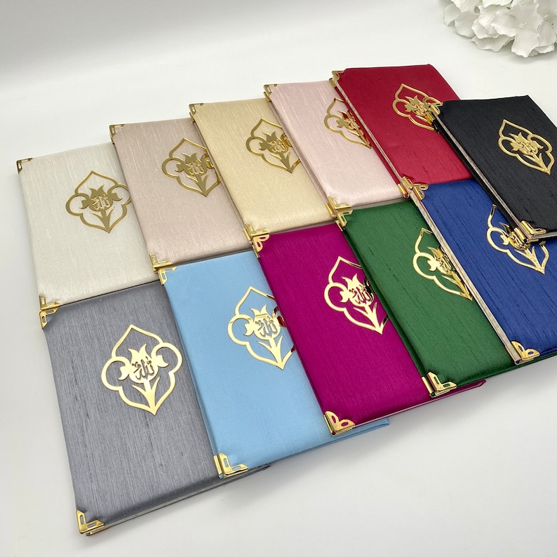 Pu&ograve; includere: Una collezione di 12 piccoli libri di preghiera rettangolari rivestiti in tessuto con dettagli dorati. Ogni libro presenta un disegno dorato di un fiore con la parola "Allah" in scrittura araba.