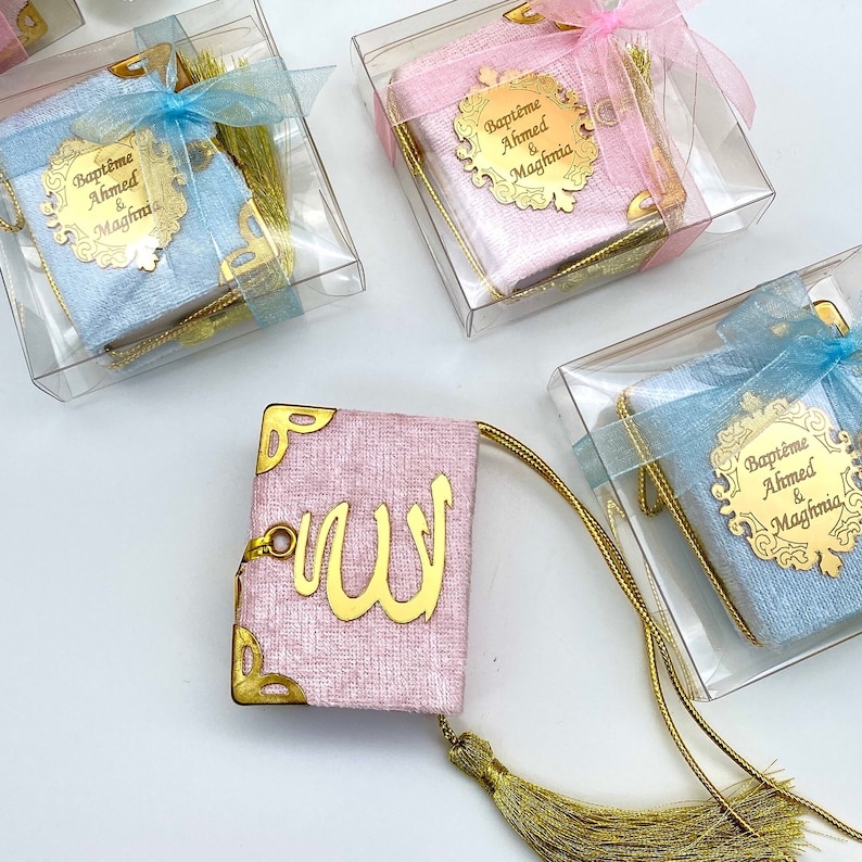 May include: Pink and blue velvet covered books with gold trim and tassels. The books have a gold inscription that reads "Bapteme Ahmed & Maghfria".