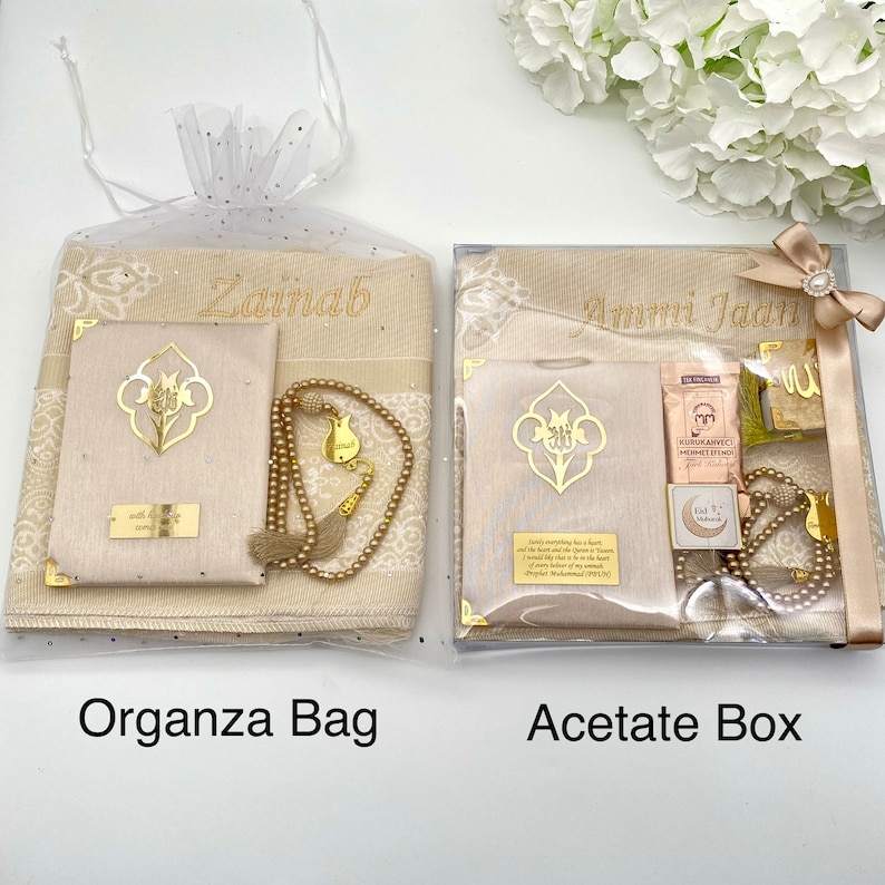 May include: Two gift sets for prayer, one in a clear organza bag and the other in a clear acetate box. Both sets include a prayer rug, a prayer book, a set of prayer beads, and a bookmark. The organza bag set is personalized with the name "Zainab" and the acetate box set is personalized with the name "Ammi Jada".