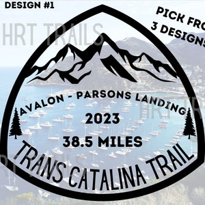 May include: Black and white graphic design of a mountain range with the text "Avalon - Parsons Landing" and "Trans Catalina Trail" in a circle. The text "2023" and "38.5 miles" are also included in the design.