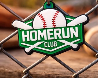 May include: A baseball-themed pendant with a chain, hanging on a chain-link fence. The pendant features a baseball design with red stitching, a green background, and the words "HOMERUN CLUB". Two white baseball bats are crossed behind the baseball.