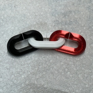 May include: Three connected chain links, one black, one white, and one red.