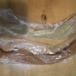 May include: Two bundles of hair extensions in clear plastic packaging. One bundle is a light blonde color, and the other is a medium auburn color. The extensions are neatly arranged and ready for use.