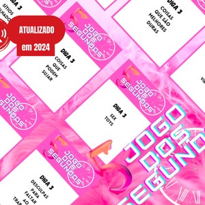 Könnte beinhalten: Rosa und weiße Karten mit dem Text "Jogo dos Segundos" (Portugiesisch für "Spiel der Sekunden") und "Diga 3" (Portugiesisch für "Sag 3") gefolgt von einer Aufforderung. Die Karten liegen auf einer rosa flauschigen Oberfläche.