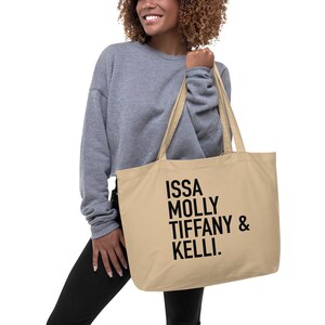 Könnte beinhalten: Eine beige Einkaufstasche mit schwarzem Text, der "ISSA MOLLY TIFFANY & KELLI." lautet.