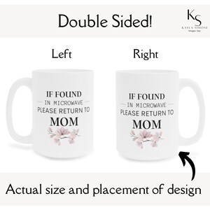 May include: White ceramic mug with a black and white design that says "If found in microwave please return to Mom" with a floral design in pink and purple. The mug is shown on both sides.