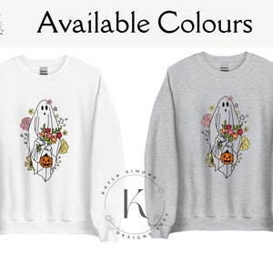 May include: Two sweatshirts with a ghost holding a pumpkin and flowers. The sweatshirt on the left is white and the sweatshirt on the right is gray. The text "Available Colours" is at the top of the image.