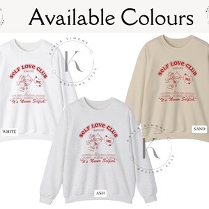 K&ouml;nnte beinhalten: Drei Sweatshirts in den Farben Wei&szlig;, Asche und Sand mit einem roten grafischen Aufdruck, der "Self Love Club" mit einem Cupido-Design und dem Text "It's Never Selfish." lautet.
