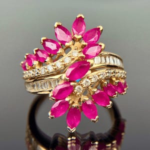 May include: A gold ring with a cluster of pink rubies and diamonds set in a floral design.