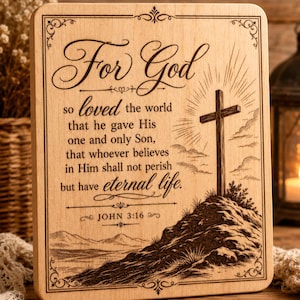 May include: A rectangular light-colored wooden plaque featuring a laser-engraved design of a cross on a hill. The text reads: For God so loved the world that he gave His one and only Son, that whoever believes in Him shall not perish but have eternal life. JOHN 3:16.