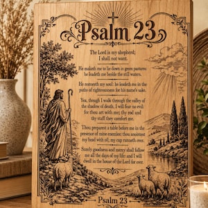 Può includere: Targa in legno con il testo del Salmo 23, con un'illustrazione incisa di un pastore con pecore e un paesaggio. La targa ha un bordo decorativo e una croce in alto.